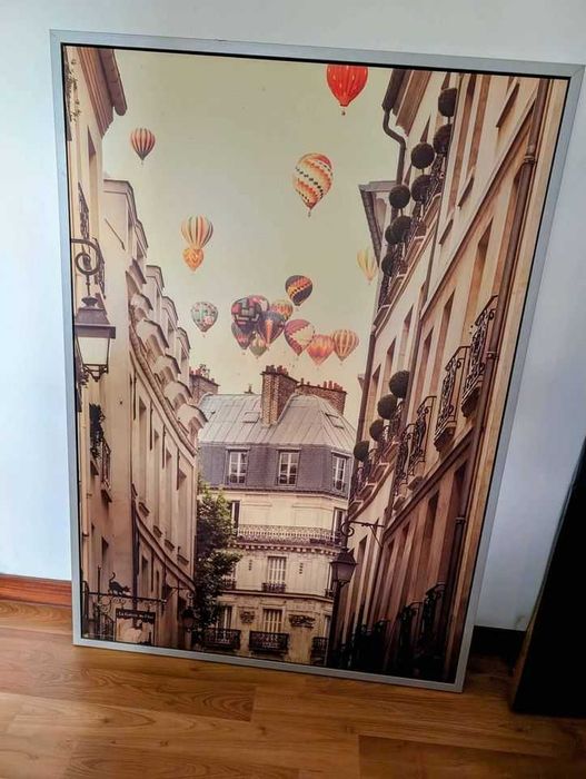 Large painting featuring a European landscape with hot air balloons in the sky