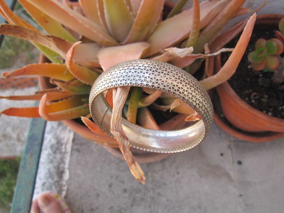 Pulseira rígida prateada com intrincado padrão geométrico triangular perfurado