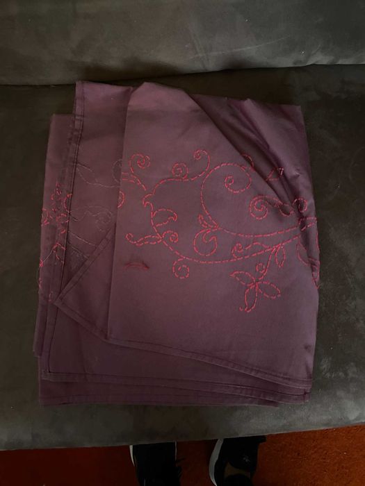 toalha roxa com um bordado em rosa