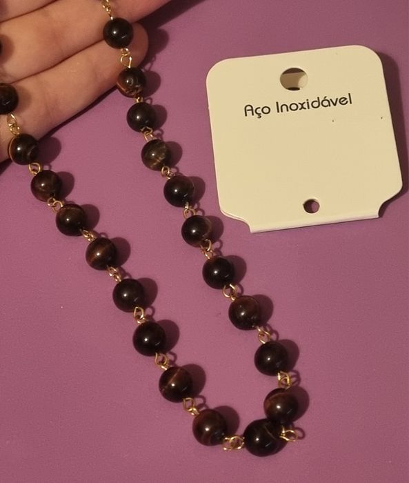 Colar dourado, em aço, às bolinhas castanhas de pedra natural "olho de gato". Tem extensor.