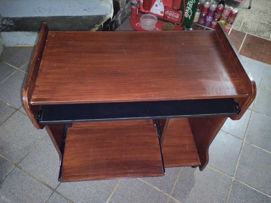 Mesa de computador em bom estado com rodas e duas prateleiras deslizan