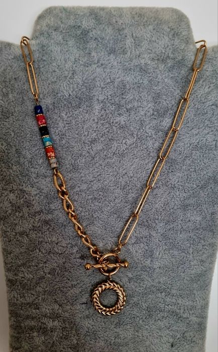 Colar dourado, em aço, assimétrico e com pedrinhas naturais coloridas.