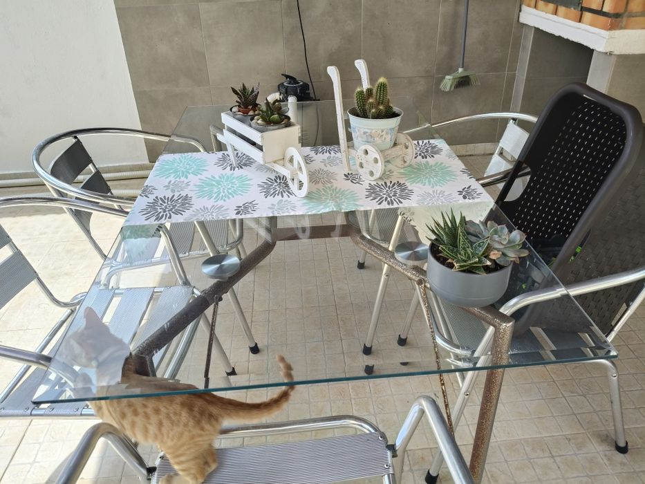 Mesa com tampo de vidro e 5 cadeiras de alumínio.