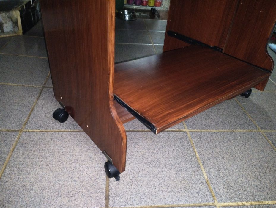 Mesa de computador em bom estado com rodas e duas prateleiras deslizan