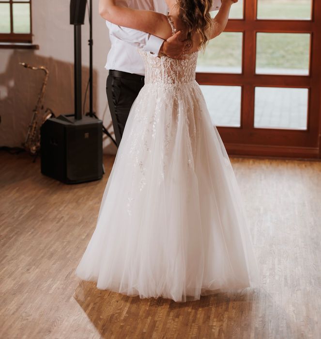 Suknia ślubna z gorsetową górą oraz kwiatowymi dekoracjami.