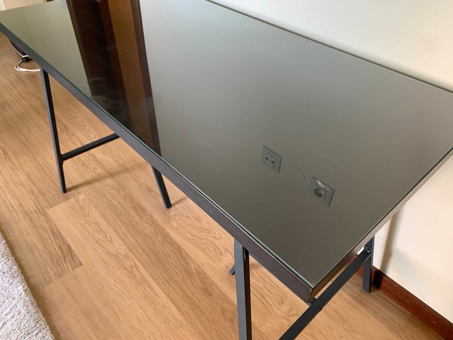 Secretária Ikea com tampo de madeira e vidro.