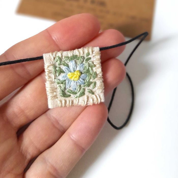 Pulseira bordada à mão com pingente de margarida azul
