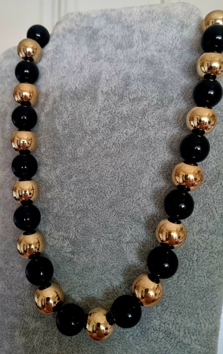 Colar dourado, em aço, às bolinhas douradas intercaladas com pretas. Leve.