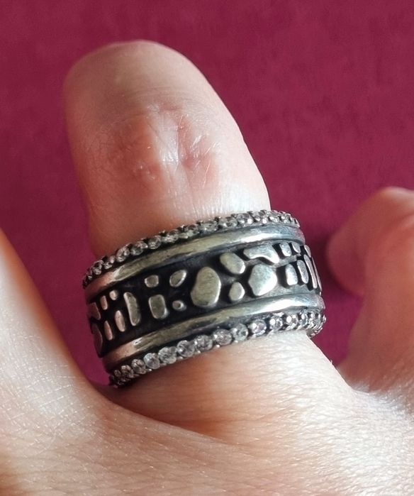 Anel prateado, em aço envelhecido, com fundo preto e zirconias. T18