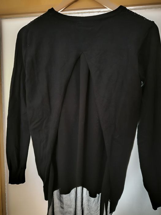 Camisola preta pedras de brilho e abertura com transparência atrás.