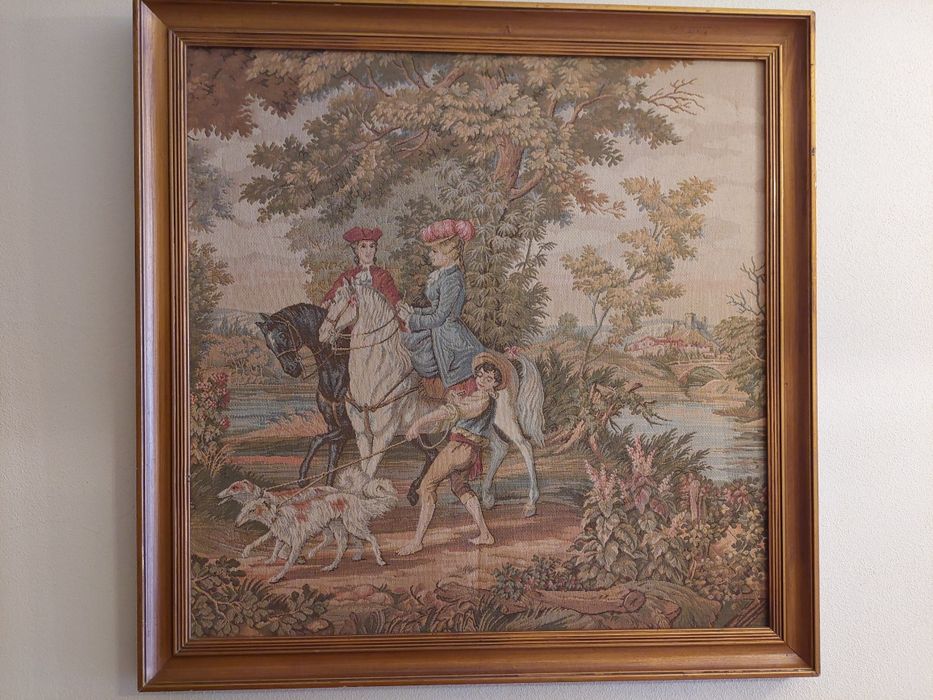 Quadro em tapeçaria com uma cena  de passeio a cavalo num bosque, com moldura em ouro velho. Dimensões  - 78x78cm.