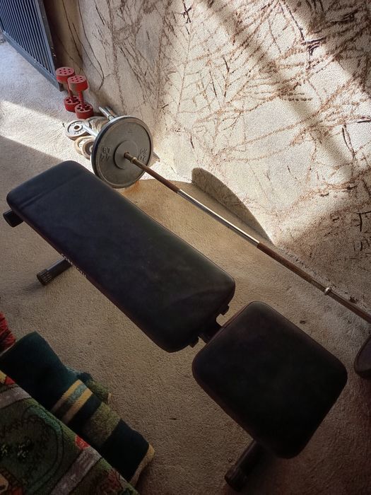 Anilhas, halteres, barras e banco de ginásio.