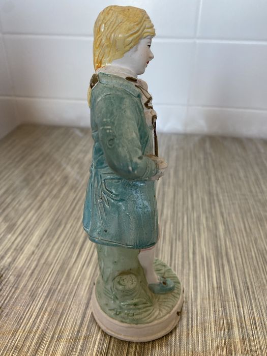 Estátua em cerâmica de um homem que segura um violino