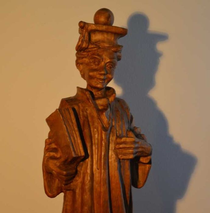 Estatueta esculpida em madeira maciça, representando um estudante universitário