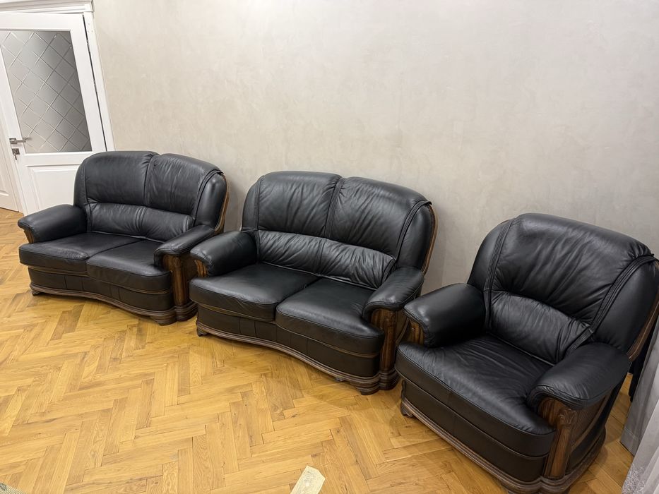 Стильний комплект: диван і крісла з натуральної шкіри чорного кольору з дерев’яними декоративними елементами.