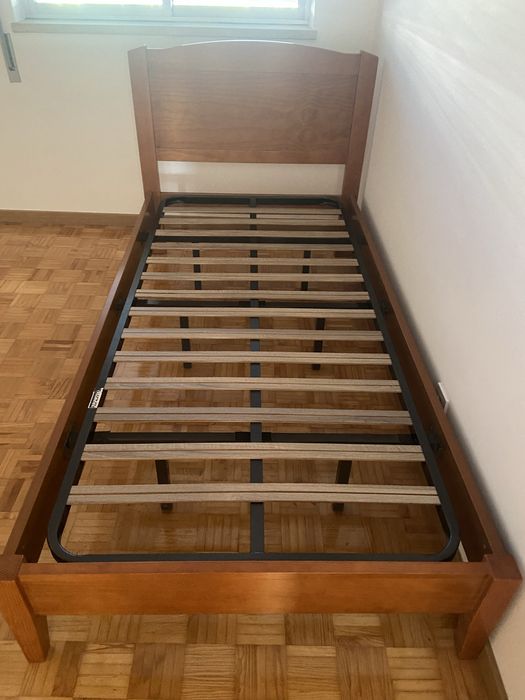 Cama individual de madeira macica e uma mesa de cabeceira