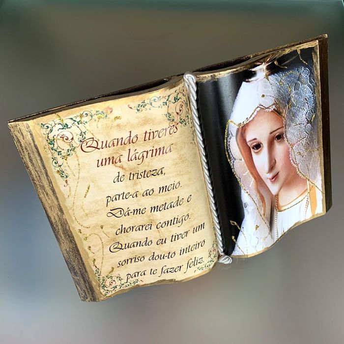 Livro aberto decorativo com Nossa Senhora e pequeno texto.