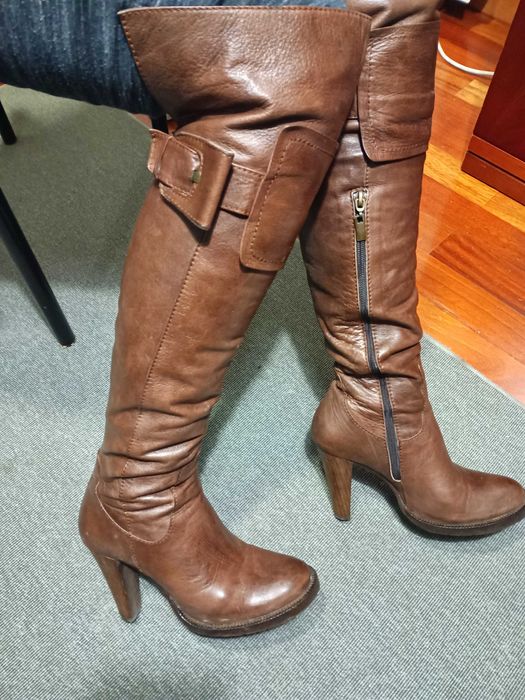 Botas castanhas em pele de cano alto ligeiramente acima do joelho