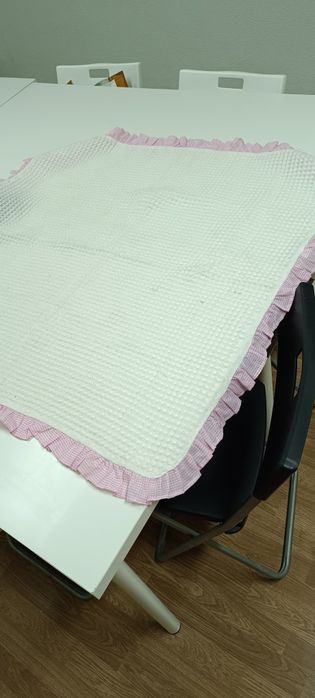 Manta de criança branca com folho e bonecos em cor de rosa . Tem umas