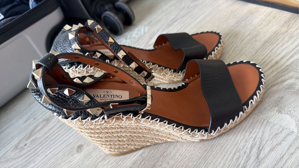 Sandália Valentino Gravani destacam-se pelo elegante desing em couro preto granulado com tachas douradas icônicas