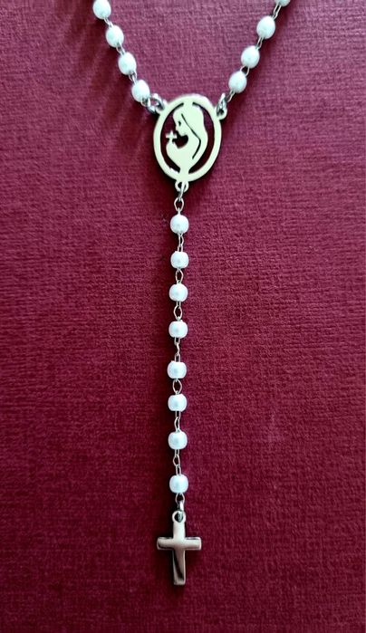 Colar prateado, em aço, em forma de terço com pequenas pérolas.