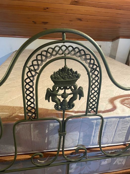 Cama de casal em ferro com colchão e estrado.