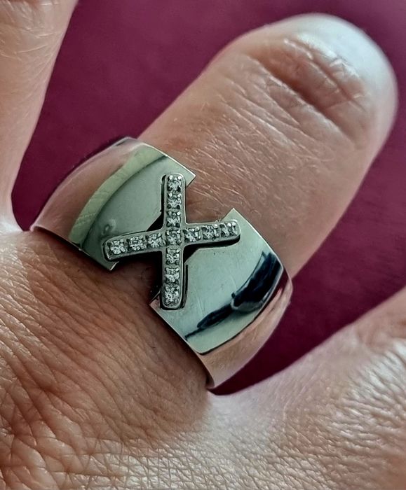 Anel grosso prateado, em aço, com um X em zirconias. T20
