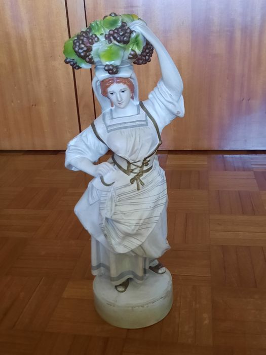 Estatueta decorativa em porcelana - camponesa com cesto de uvas