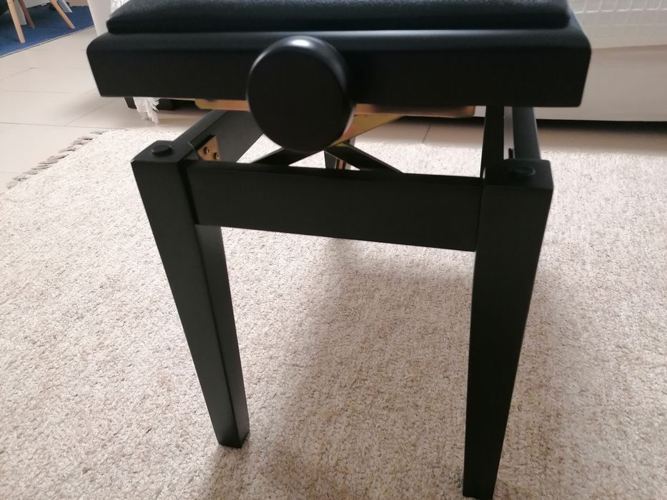 Banco de piano com assento e pele preta.