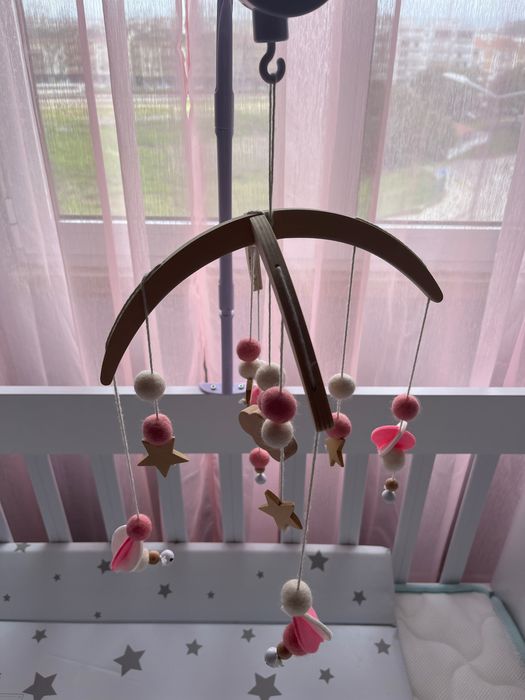 Berço de bebê com balanço, com um colchão e um trocador de fraldas.