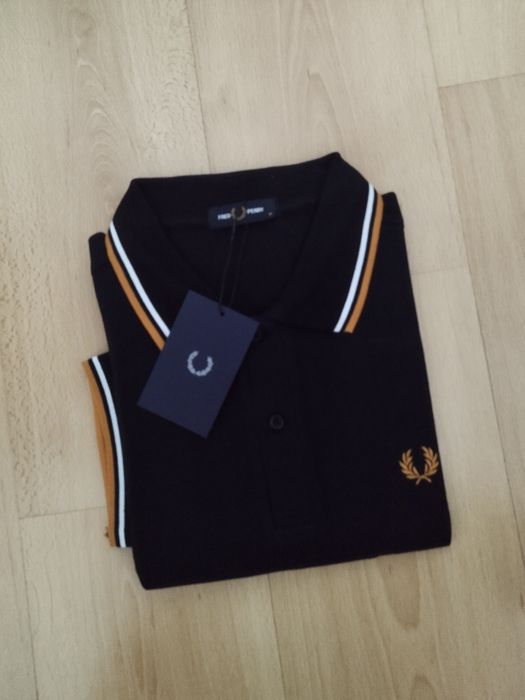 Pólo Fred Perry preto com listas brancas e amarelas.