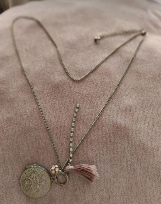 Colar com medalhão floral e borla rosa.