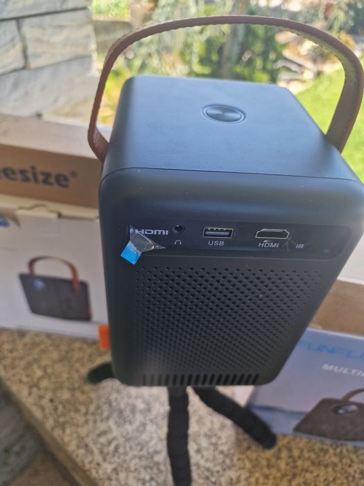 projetor portátil FunFlix G1 com alça de transporte.O dispositivo possui conectividade Wi-Fi 5G oferta de tripé