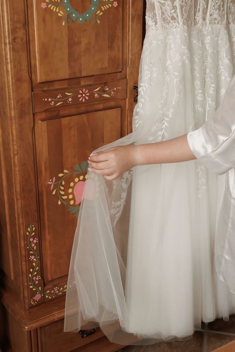 Suknia ślubna z gorsetową górą oraz kwiatowymi dekoracjami.