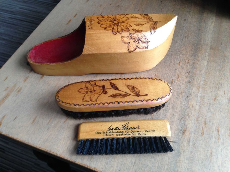 Szczotki do ubrań i butów w zawieszanym drewnianym schowku.