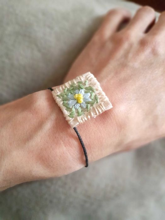 Pulseira bordada à mão com pingente de margarida azul