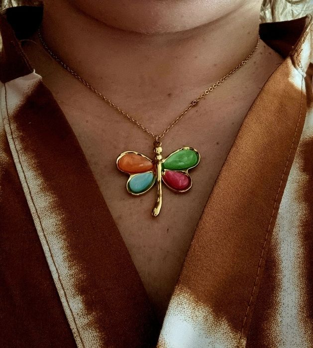 Colar dourado, em aço, com libelinha colorida. Tem extensor