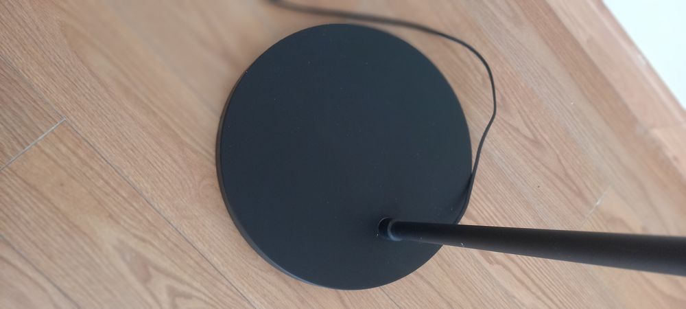 Candeeiro alto curvo, com base em metal preto.