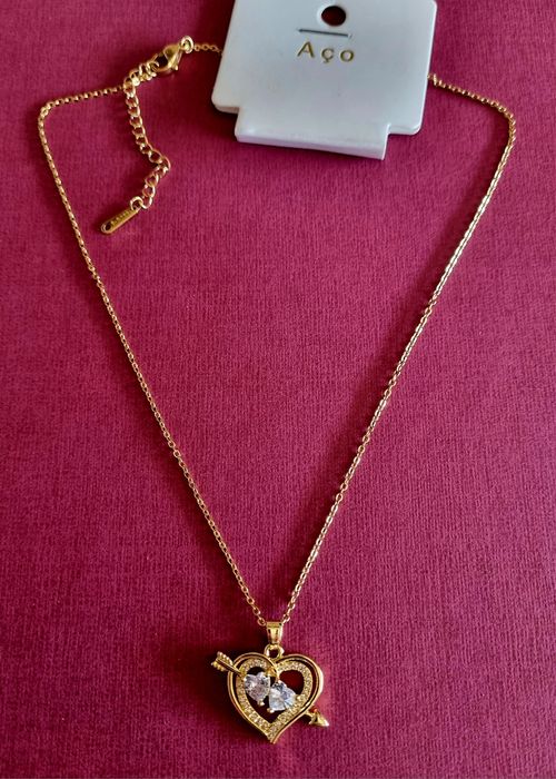 Colar dourado, em aço, com 2 corações unidos por uma flecha.