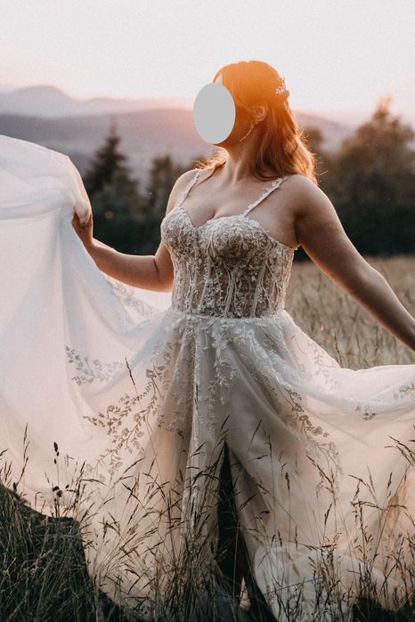 Suknia ślubna z gorsetową górą oraz kwiatowymi dekoracjami.