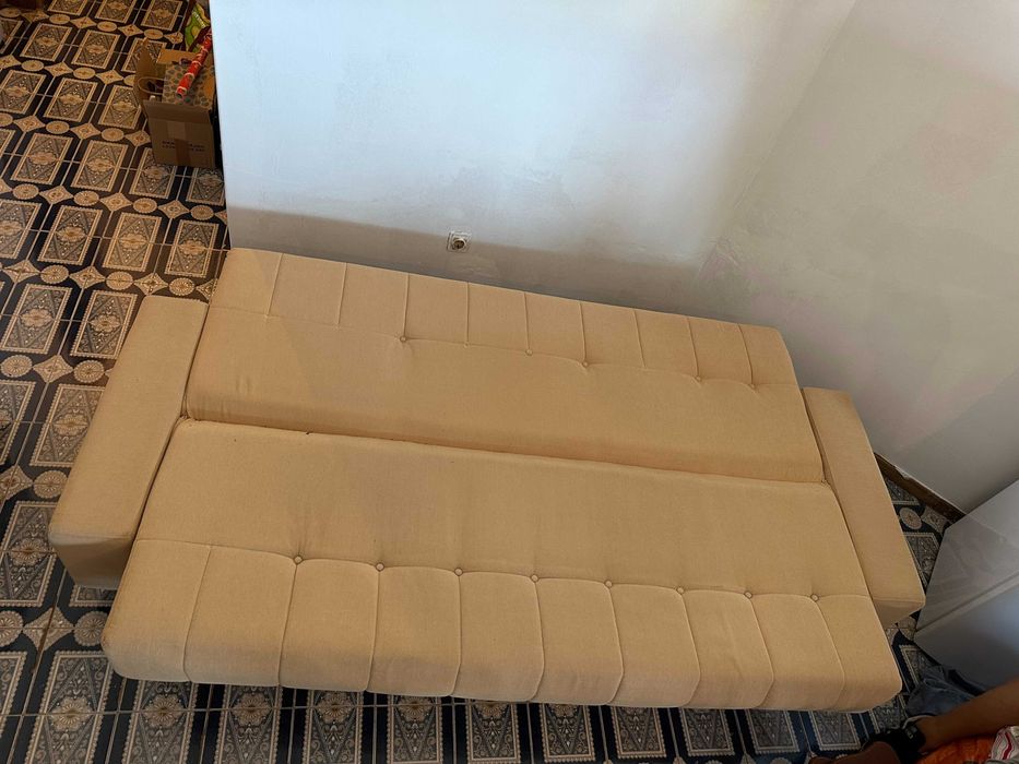 Sofá-cama bege em bom estado.