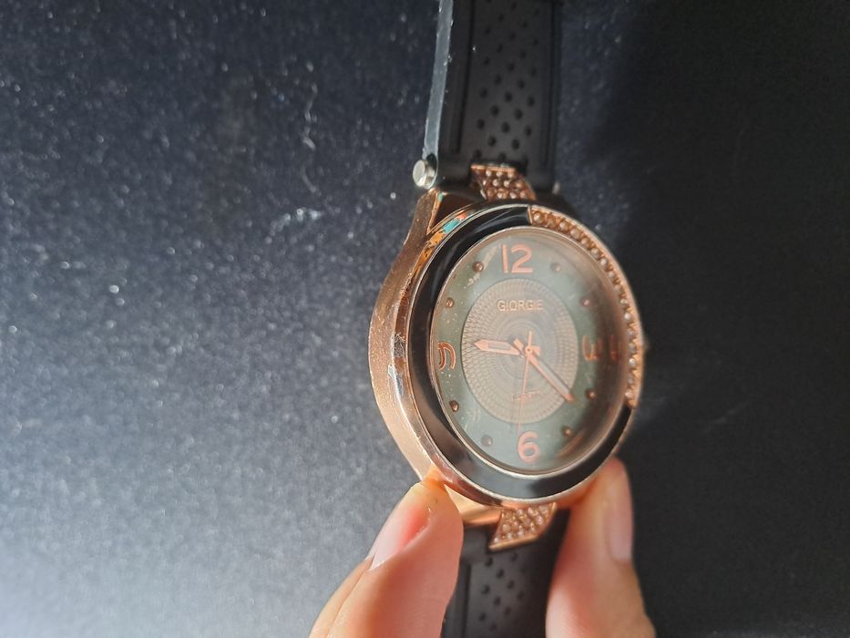 Relógio dourado e preto com pedrinhas