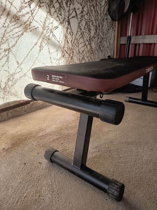 Anilhas, halteres, barras e banco de ginásio.