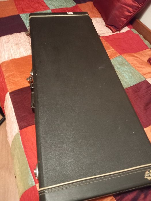 Guitarra eléctrica em caixa com suporte e amplificador