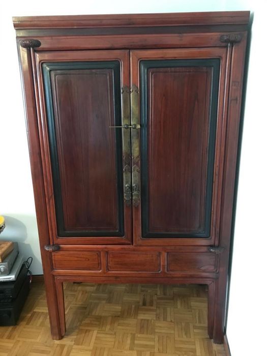Armário de madeira avermelhada estilo oriental com portas e gavetas