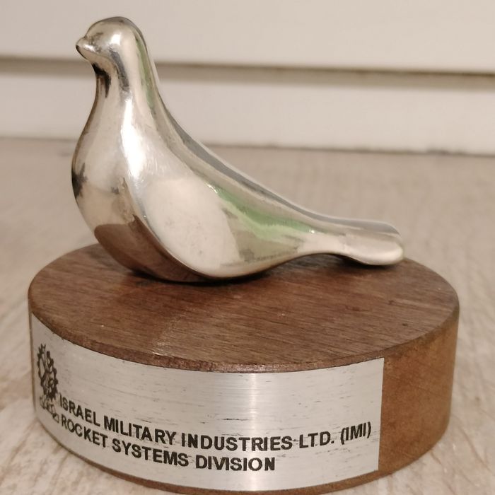 srebrna figurka ptaka (symbolu pokoju) na drewnianym stojaku