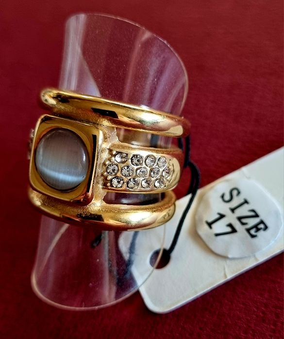 Anel dourado, em aço, com zirconias e uma pedra "olho de gato". T17