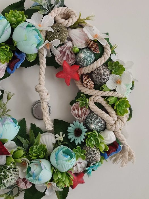 Guirlanda artesanal marítima com flores, conchas e farol decorativo