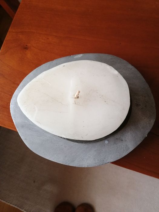 Vela branca rodeada com metal e com suporte metálico