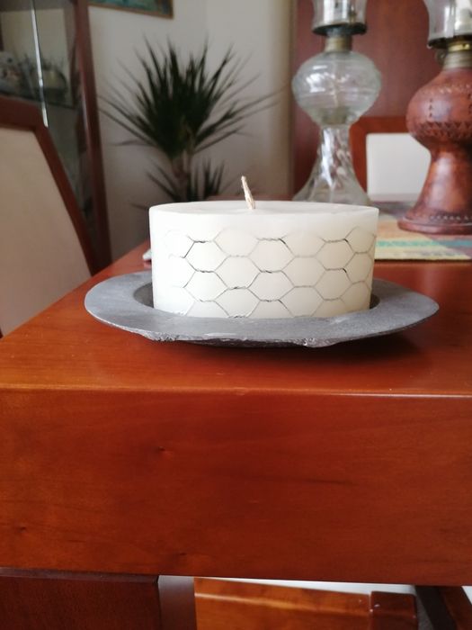 Vela branca rodeada com metal e com suporte metálico